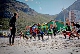 Vrijwilligerswerk in Zuid-Afrika:Een vrijwilliger op het surf project in Kaapstad geeft instructies aan de kinderen die willen leren surfen. Een vrijwilliger op het surf project in Kaapstad geeft instructies aan de kinderen die willen leren surfen.